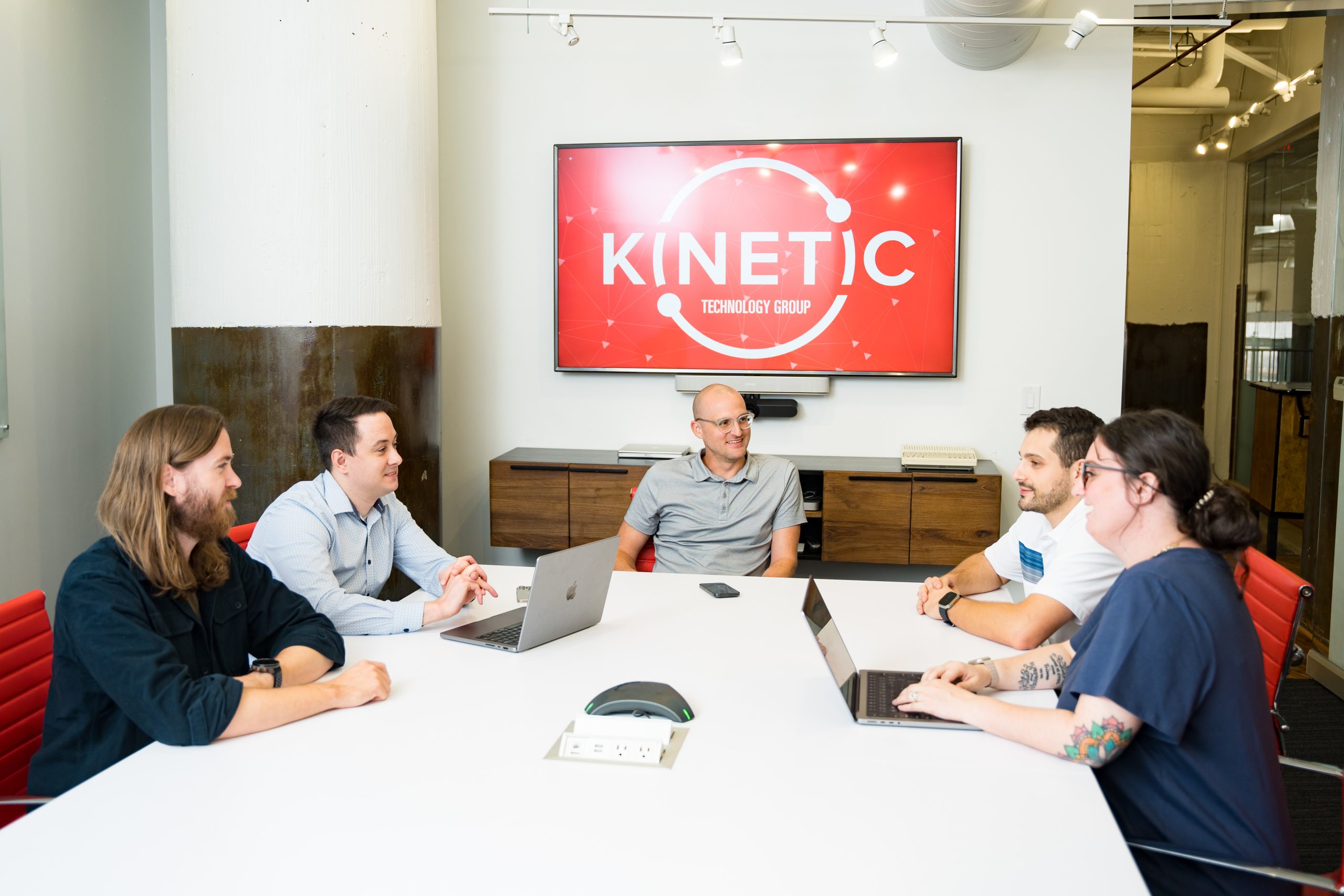 Kinetic Technology Group employees meeting around a conference table